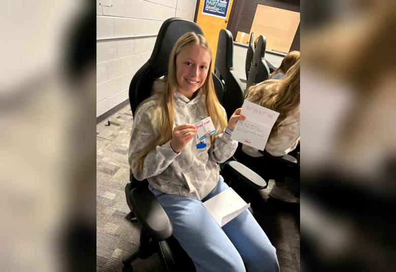 Osage HS student seated in class holding a handwritten response and free drink coupon from BUBBL'R