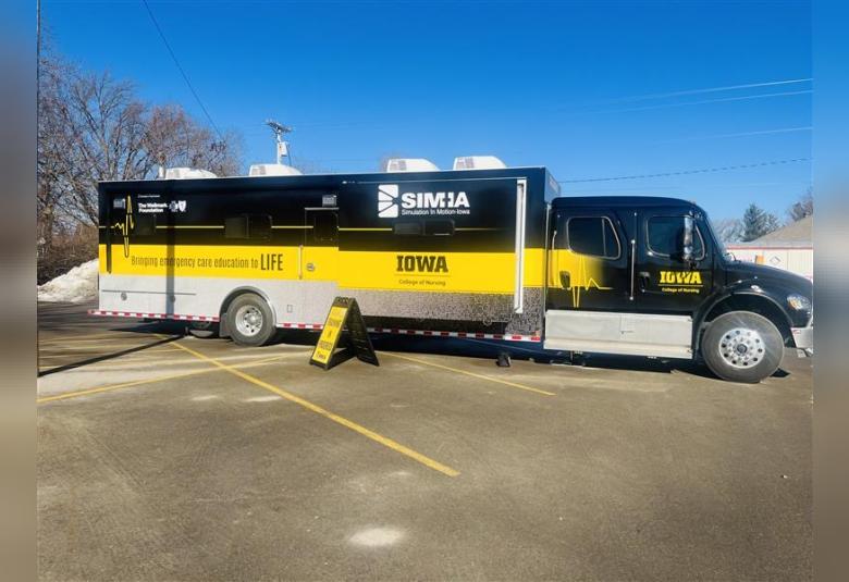 Black and yellow University of Iowa Simulation in Motion-Iowa mobile medical training truck parked in Osage for hospital staff trauma training.